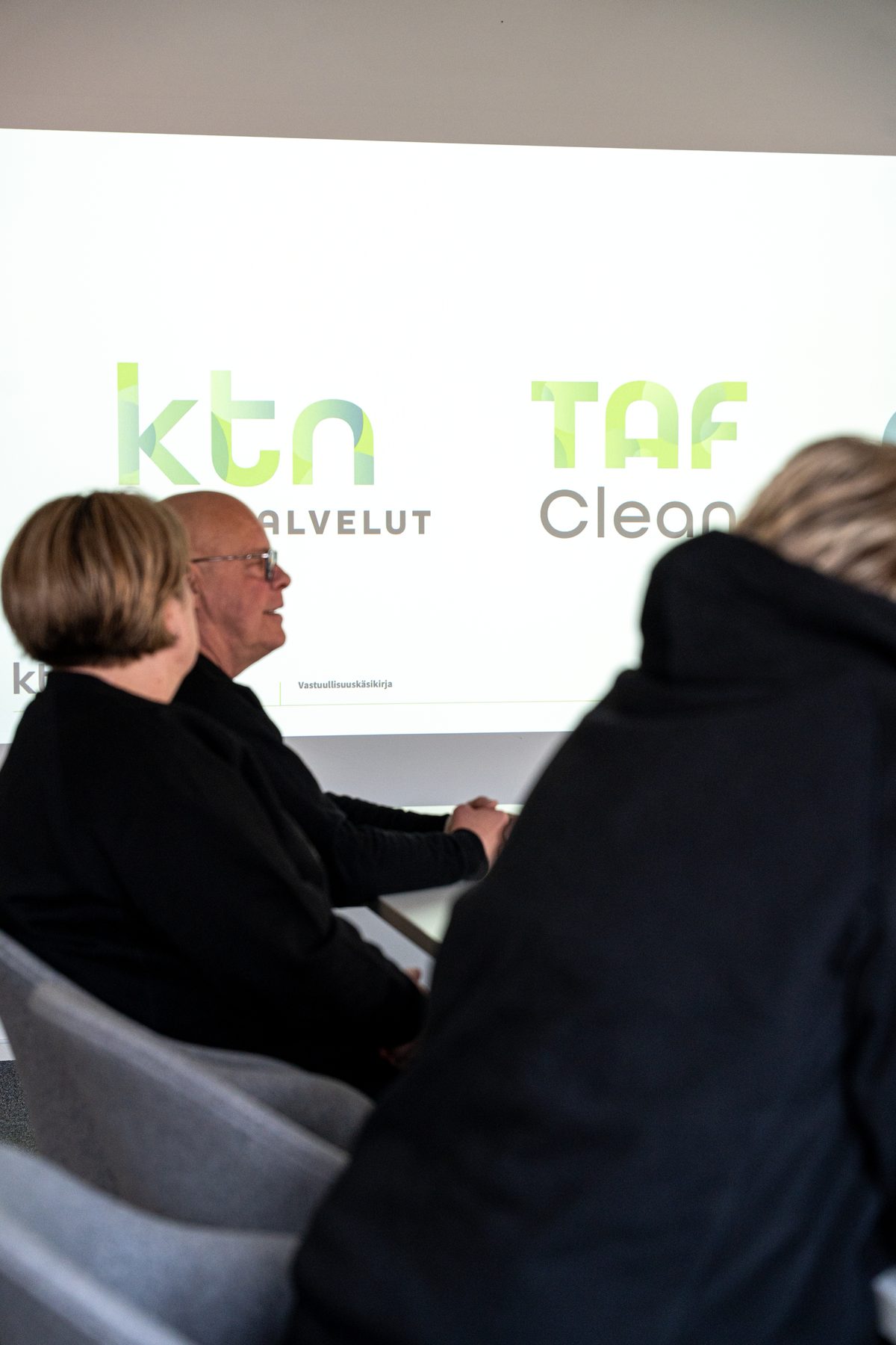 KTN:n ja TAF-Cleanin logot palaverin näytöllä, edessä KTN:n väkeä